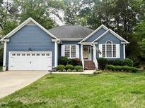 Charming single-story home featuring a blue exterior, white trim, a well-manicured lawn, and an attached two-car garage at 8712 Attingham Dr, Raleigh, NC 27615