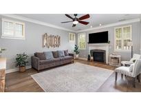 Cozy living room featuring a decorative fireplace, ceiling fan, and neutral color scheme at 1209 Shasta Daisy Dr, Wake Forest, NC 27587