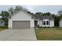 Charming single-story home featuring a gray garage door, light gray siding, and a well-manicured lawn at 139 Oakfield Trace Dr, Four Oaks, NC 27524