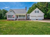 Charming home with a well-maintained lawn, attached garage, and front porch with an American flag at 1576 Cheves Rd, Zebulon, NC 27597