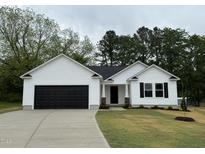 Charming one-story white home with a black garage door and landscaped front yard at 163 Oakfield Trace Dr, Four Oaks, NC 27524