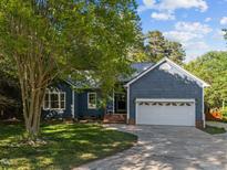 Charming blue home featuring a manicured lawn, mature trees, and a two-car garage at 2123 Fountain Ridge Rd, Chapel Hill, NC 27517