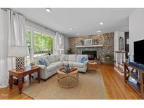 Inviting living room features a stone fireplace, hardwood floors, and a large window with natural light at 305 Clarendon Cres, Raleigh, NC 27610