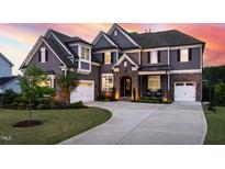 Stunning two-story home with a stone-accented entrance and well-manicured lawn at sunset at 3215 Bellamy Ridge Dr, Apex, NC 27523