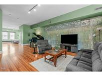 Spacious living room featuring a piano, hardwood floors, and unique accent wall at 323 W Main St # C, Durham, NC 27701