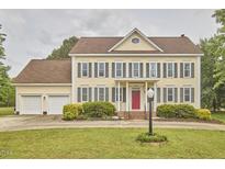 Traditional two-story home with yellow siding, a red door, a well-manicured lawn, and a two-car garage at 3809 Victorian Grace Ln, Apex, NC 27539
