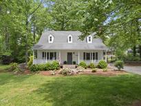 Charming home featuring a covered front porch, dormer windows, and a well-manicured lawn with lush landscaping at 404 Trappers Run Dr, Cary, NC 27513