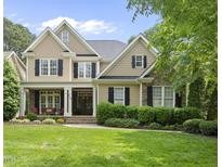 Charming two-story home with stone accents, black shutters, a well-manicured lawn and covered front porch at 716 Streamwood Dr, Holly Springs, NC 27540