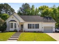Charming white home featuring an attached garage, well-manicured lawn, and inviting front entrance at 8401 Hobhouse Cir, Raleigh, NC 27615