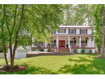 Charming home with a red door, white pillars, and a wide front porch, set on a lush lawn at 1107 Daleland Dr, Raleigh, NC 27612