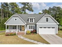 Charming home featuring a welcoming front porch, well-manicured lawn, and an attached two car garage at 1427 Bungalow Ave, Durham, NC 27703