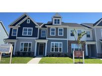 Modern townhome with a striking blue and gray exterior, complemented by lush green grass and professional landscaping at 1565 Wendell Valley Blvd, Wendell, NC 27591