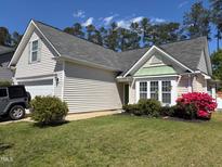 Charming single-story home with manicured lawn, flowering shrubs, and a two-car garage at 205 Braxcarr St, Holly Springs, NC 27540