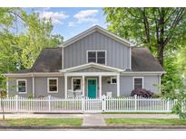 Charming gray two-story home featuring a white picket fence and a vibrant blue front door, surrounded by lush greenery at 219 Northwood Cir, Durham, NC 27701