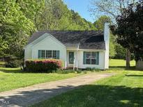 Charming home featuring a well-manicured lawn, flowering shrubbery, and a classic white exterior at 409 Vista Springs Cir, Holly Springs, NC 27540