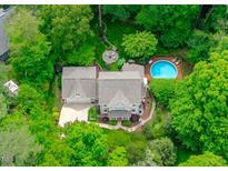 Stunning aerial view of a home with a pool, fire pit, and lush green landscaping surrounded by mature trees at 4405 New Brighton Dr, Apex, NC 27539