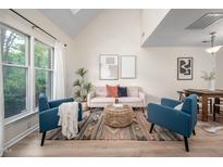 Bright living room featuring vaulted ceilings, large windows, stylish furniture, and wood-look flooring at 53 Forest Oaks Dr, Durham, NC 27705