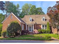 Charming brick home with a well-manicured lawn, mature trees, and a decorative wrought iron fence at 8 Greenside Ct, Durham, NC 27707