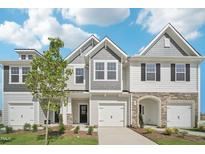 Charming townhome exterior featuring a mix of siding and stone accents, complemented by a well-manicured lawn and blue skies at 908 Kensley Grove Ln # 68, Fuquay Varina, NC 27526