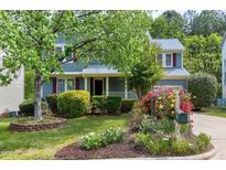 Charming blue two-story home with a lush front yard and a beautiful flower garden at 103 Trent Woods Way, Cary, NC 27519
