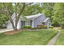 Charming home featuring a two-car garage, manicured lawn, and lush landscaping with mature trees at 115 Standish Dr, Chapel Hill, NC 27517