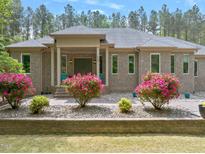 Charming brick home with a covered porch, flowering bushes, and meticulously maintained landscaping at 120 Wood Lake Dr, Fuquay Varina, NC 27526