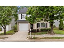 Charming two-story home with beige siding, black shutters, attached garage, and manicured landscaping at 125 Occidental Dr, Holly Springs, NC 27540