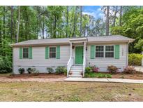 Charming single-story home with vibrant green door and shutters, landscaped garden, and inviting entrance at 1703 Cranston Road Rd, Garner, NC 27529