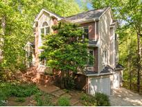 Charming home featuring a mix of brick and siding, set amidst lush trees and a brick walkway leading to the entrance at 205 Glenview Pl, Chapel Hill, NC 27514
