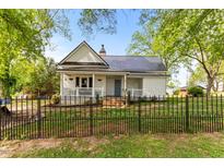 Charming white home with a black metal roof, front porch, and wrought iron fence at 2102 Courtland Dr, Sanford, NC 27330