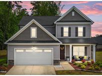 Charming two-story home featuring a well-manicured lawn, inviting porch seating, and a two-car garage at 2215 Montebell View Dr, Fuquay Varina, NC 27526