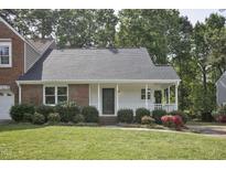 Charming single-story home featuring a welcoming front porch, lush landscaping, and a well-maintained lawn at 2611 Sawmill Rd, Raleigh, NC 27613
