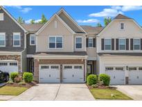 Charming townhome featuring a brick facade, a two-car garage, and beautifully landscaped front yard at 4137 Lofty Ridge Pl, Morrisville, NC 27560