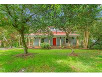 Charming two-story home with a red metal roof, a inviting front porch, and mature trees in a lush green yard at 429 N Asheboro St, Liberty, NC 27298
