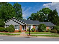 Charming brick home with a gray roof, lush landscaping, and inviting curb appeal, offering classic suburban comfort at 4900 Old Millcrest Ct, Raleigh, NC 27609