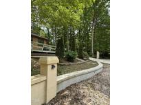Landscaped front yard with a winding driveway, retaining wall, and a glimpse of the home's deck at 5601 Plum Nearly Ct, Raleigh, NC 27610
