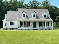 Charming home featuring a metal roof, classic white siding, and a welcoming front porch at 675 Anderson Creek Rd, Henderson, NC 27537