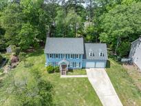 Aerial view of a two story home with a two car garage and large front yard landscaped with mature trees at 7209 Halstead Ln, Raleigh, NC 27613