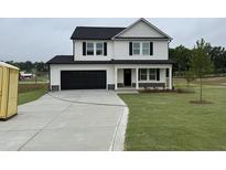 New two-story home with a black door, black shutters, black garage, and a well-manicured lawn at 10 Silver Ct, Smithfield, NC 27577
