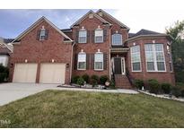 Beautiful two-story brick home featuring an attached two car garage and manicured landscaping at 102 Revere Forest Ct, Cary, NC 27519