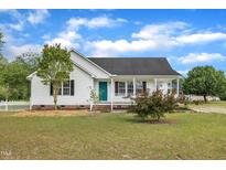 Charming home featuring a covered porch, white picket fence and well-manicured lawn at 112 Edmondson Dr, Willow Springs, NC 27592