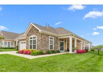 Beautiful single-story home featuring stone accents, well-manicured lawn, and vibrant flowerbeds at 122 Tall Timber Dr, Gibsonville, NC 27249