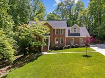 Beautiful brick home with a well-manicured lawn and mature trees on a sunny day at 12200 Glenlivet Way, Raleigh, NC 27613
