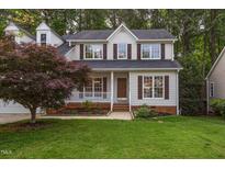 Charming two-story home with a well-manicured lawn and a cozy front porch surrounded by lush greenery at 131 Longbridge Dr, Cary, NC 27518