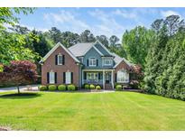 Traditional brick and siding home with manicured lawn, lush landscaping, and covered front porch at 2633 Penfold Ln, Wake Forest, NC 27587