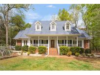 Charming one-story home featuring a welcoming front porch, dormer windows, brick stairs, and mature landscaping at 2925 Ericka Dr, Hillsborough, NC 27278