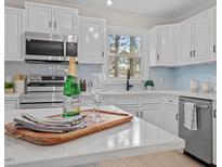 Modern kitchen featuring white cabinets, stainless steel appliances and light backsplash at 3408 Brentwood Rd, Raleigh, NC 27604