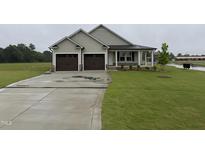 Charming home featuring a two-car garage, a covered porch, and a well-maintained lawn at 56 Ruskin Dr, Smithfield, NC 27577