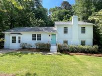 Charming white two-story home with a teal front door, mature landscaping, and a well-maintained lawn at 5817 Wintergreen Dr, Raleigh, NC 27609