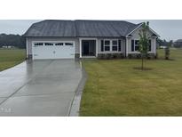 Charming single-story home with a two-car garage, well-maintained lawn, and lovely landscaping at 72 Ruskin Dr, Smithfield, NC 27577